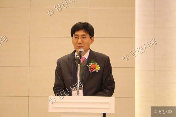 안경을 쓴 남성이 마이크가 설치된 연단에서 발언하고 있다