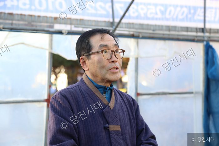 한 남성이 야외에서 인터뷰를 하거나 말을 하고 있다.