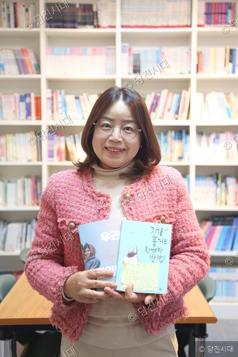 강순희 원장이 학원 교재를 들어 보이며 미소 짓고 있다.