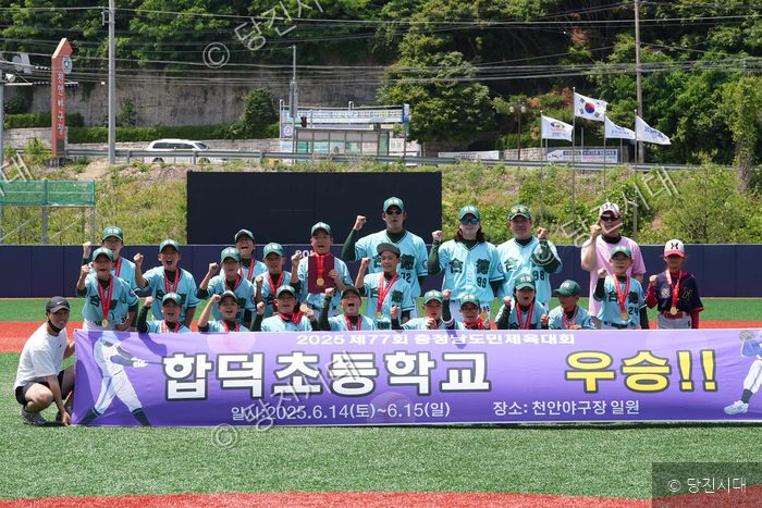 합덕초등학교 야구부원들과 코칭스태프가 도민체육대회 우승 현수막을 들고 기념촬영을 하고 있다.