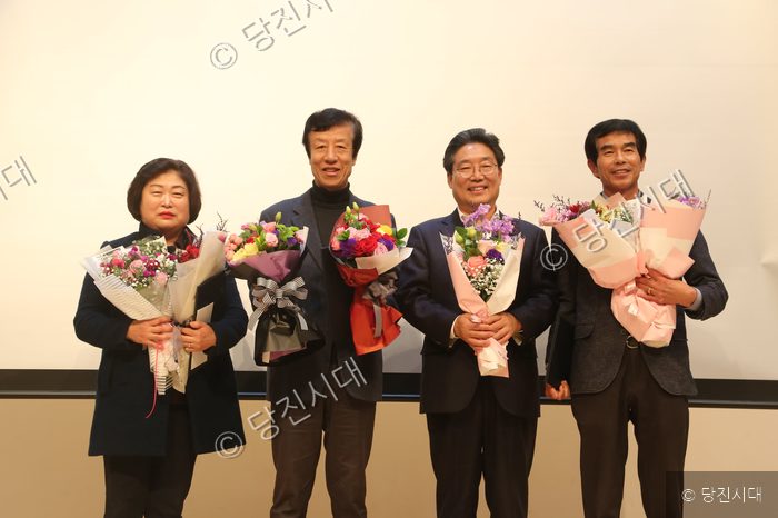 네 명의 주민이 성과공유회에서 꽃다발을 들고 기념 촬영을 하고 있다.