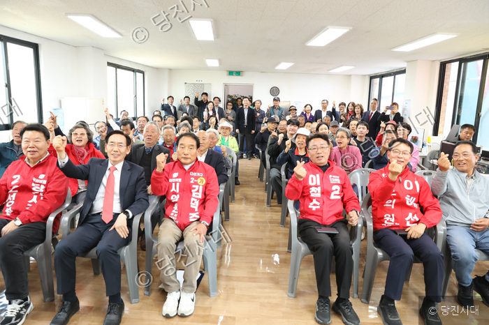 실내에 모인 사람들이 손을 들어 올리며 구호를 외치고 있다.