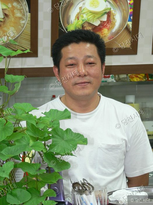 음식점 대표가 식당 안에서 포즈를 취하고 있다.
