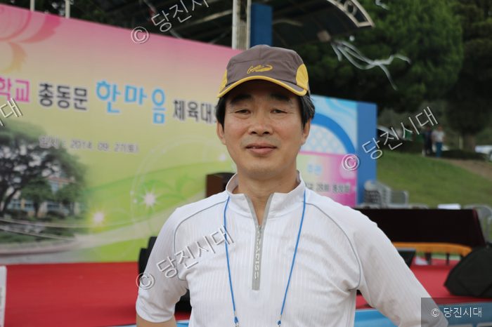 체육대회 행사에 참석한 남성이 카메라를 향해 미소 짓고 있다.