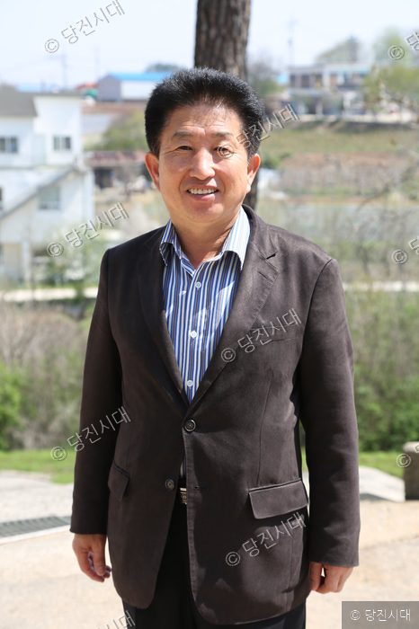 정근옥 신평면 주민자치협의회장이 야외에서 미소 짓고 있다.