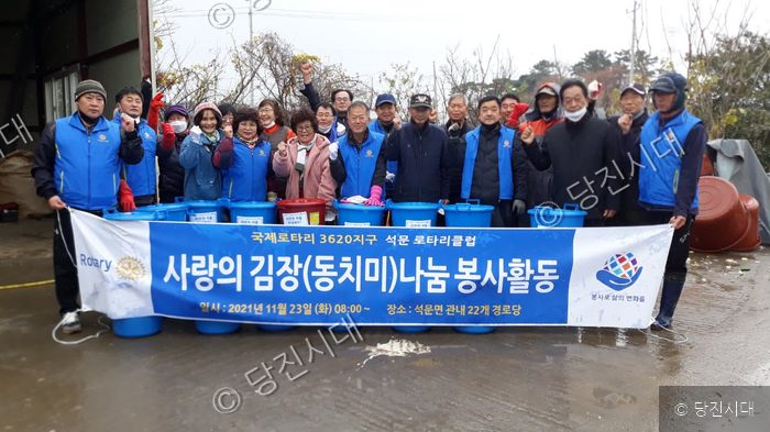 석문로타리클럽 회원들이 사랑의 김장(동치미) 나눔 봉사활동을 기념하고 있다.
