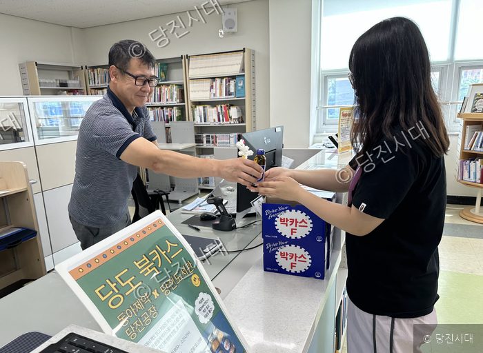 도서관 서은금 관장이 대출자에게 피로회복제를 건네고 있다.