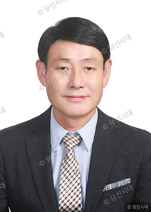 충남도의원 후보가 정장을 입고 정면을 바라보며 서 있다.