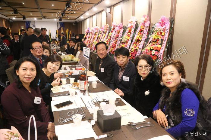향우회 회원들이 식사 자리에서 카메라를 향해 포즈를 취하고 있다.