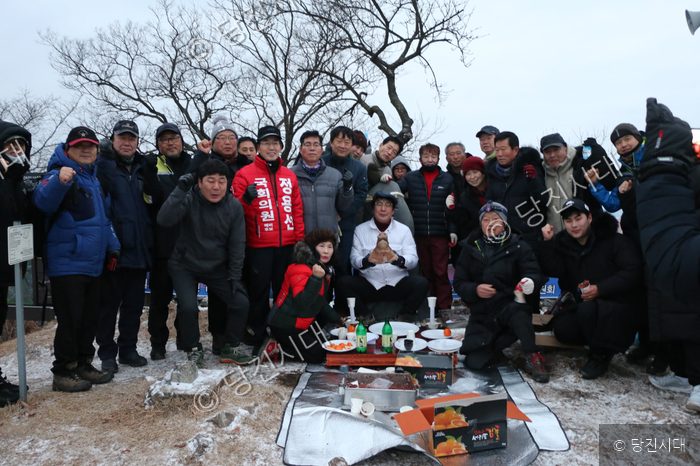 등산객들이 야외에 모여 새해 음식을 나누며 해맞이 행사를 하고 있다.