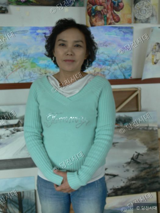 차선영 씨가 미술 작품이 걸린 전시실에서 미소를 지으며 포즈를 취하고 있다.