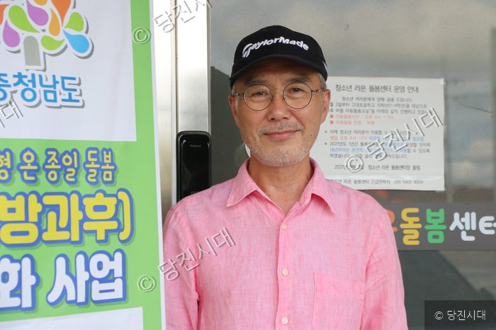 한 남성이 돌봄센터 앞에서 미소 짓고 있다.