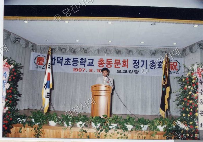 합덕초등학교 총동문회 정기총회에서 한 남성이 강대 상에서 발언하고 있다.