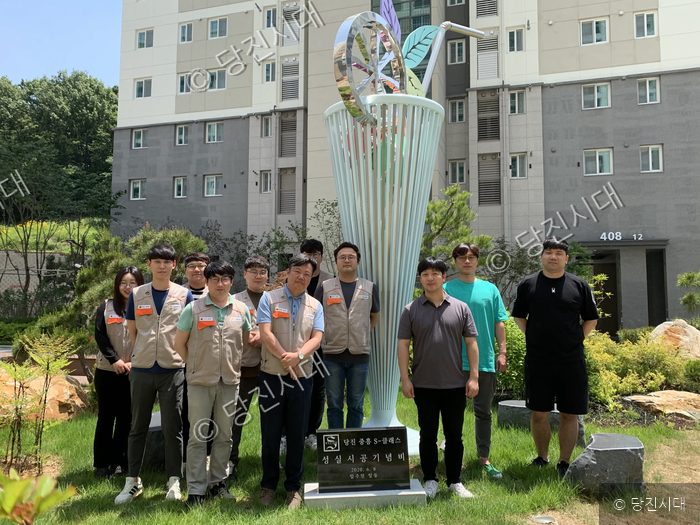 아파트 단지 내에서 입주민들이 건설사에 감사패를 전달한 후 기념촬영을 하고 있다.
