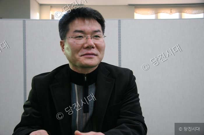 남성이 인터뷰를 위해 미소 지으며 앉아 있다.