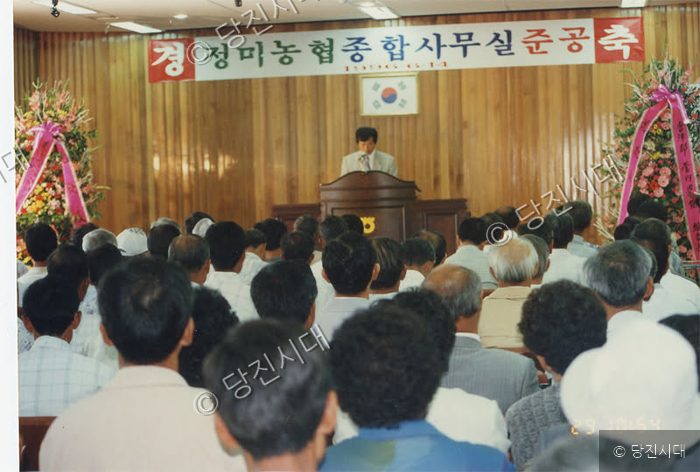 정미농협 종합사무실 준공식에서 사람들이 기념 행사를 지켜보고 있다.