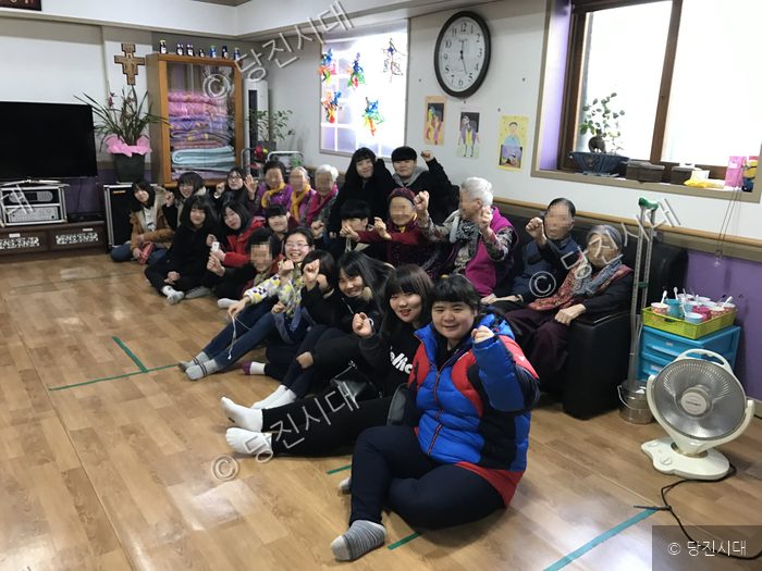 실내에 모인 사람들이 손을 들어 포즈를 취하고 있다.