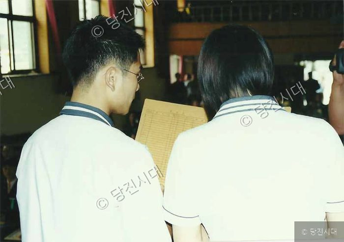 두 사람이 나란히 서서 서류를 살펴보고 있다.