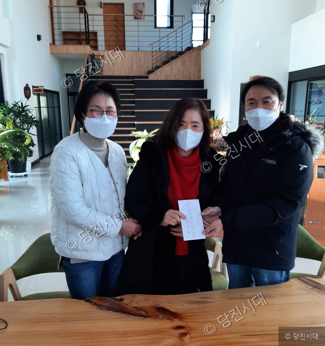 세 사람이 실내에서 후원금을 전달하며 기념 촬영을 하고 있다.