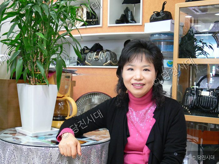 여성이 상점에서 밝은 표정으로 카메라를 바라보고 있다.