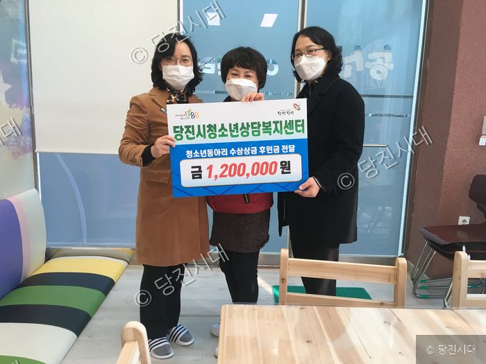세 사람이 후원금 전달을 기념하며 기념 촬영을 하고 있다.