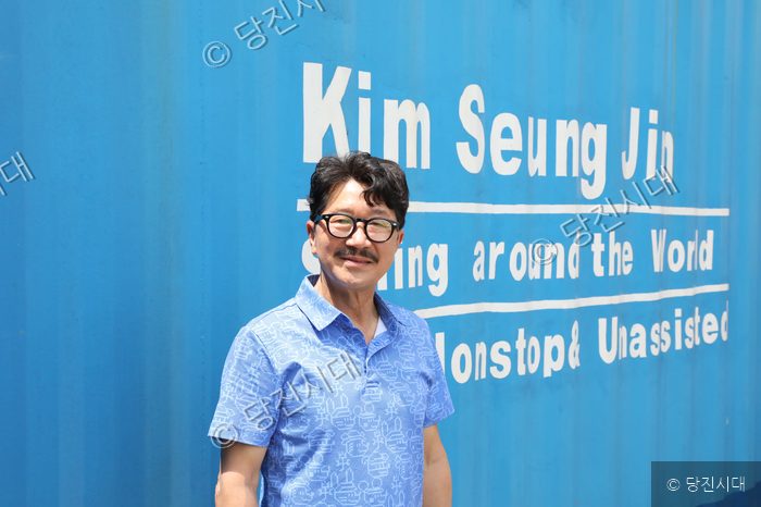김승진 선장이 파란색 배경 앞에서 포즈를 취하고 있다.