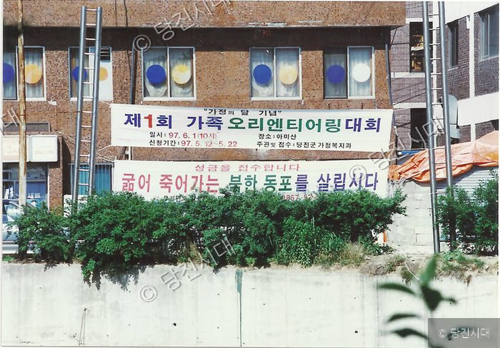 건물 외벽에 제1회 가족 오리엔티어링 대회 현수막이 걸려 있다.