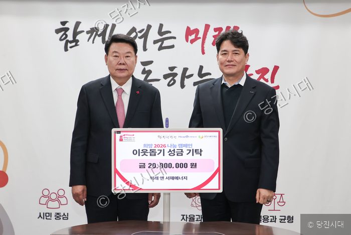 두 남자가 이웃돕기 성금 기탁 기념 피켓을 들고 서 있다.