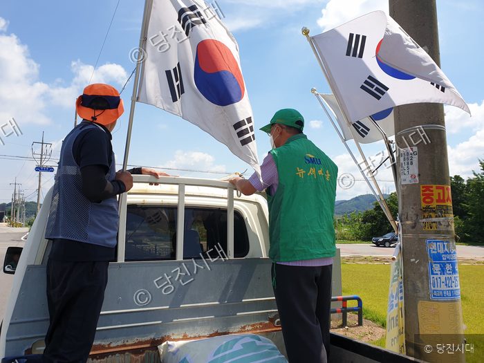 두 남성이 트럭 적재함에서 태극기를 정비하고 있다.
