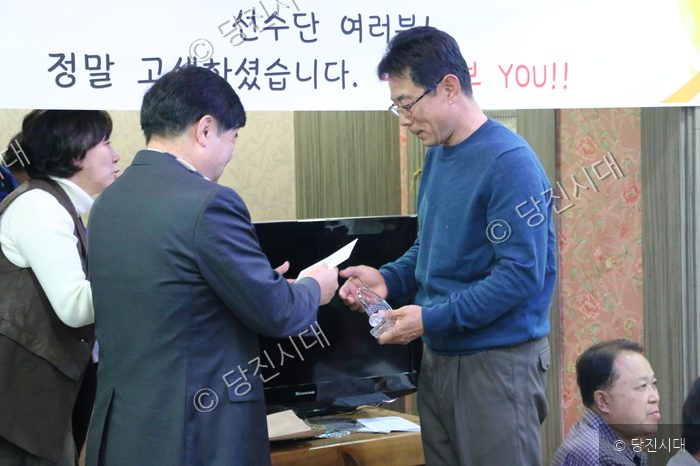 한 남성이 실내에서 감사패와 격려금을 전달받고 있다.