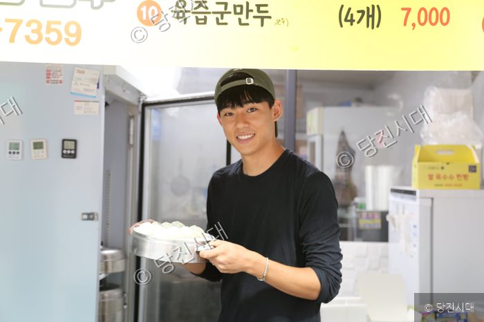 만두 가게 대표가 갓 쪄낸 만두가 담긴 찜기를 들고 미소 짓고 있다.
