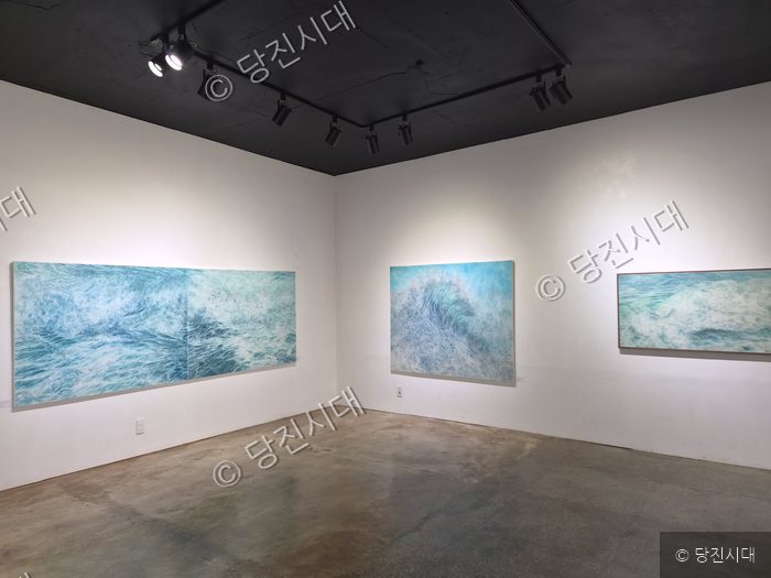갤러리에 송해석 작가의 파도 그림 작품들이 전시되어 있다.