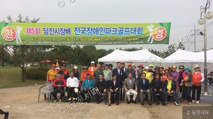 참가자들이 당진시장배 전국장애인파크골프대회 현수막 아래에서 기념촬영을 하고 있다.