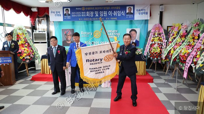 국제로타리 3620지구 당진골드로타리클럽 관계자들이 회장 이·취임식 행사에서 클럽기를 흔들고 있다.