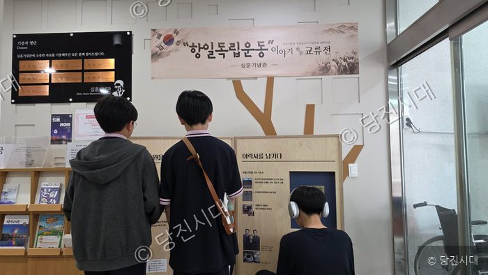 세 명의 학생이 심훈기념관 전시물을 관람하고 있다.