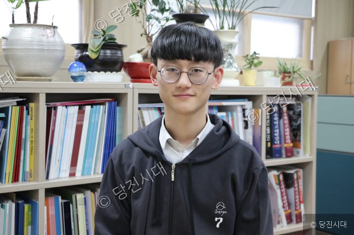 서야고등학교 학생이 교실에서 책장을 배경으로 미소 짓고 있다.
