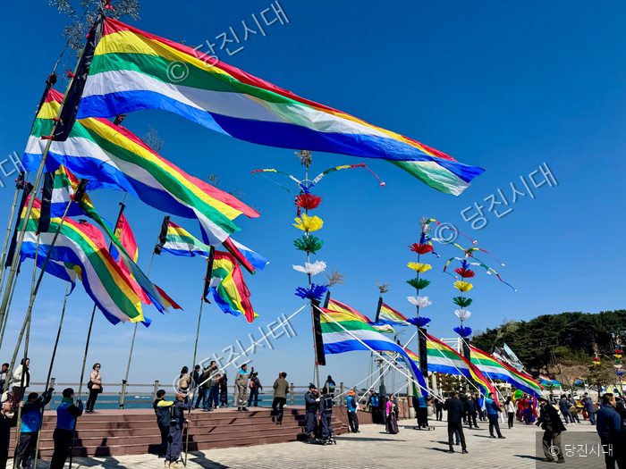 주민들이 안섬당제 행사장에서 오색 깃발을 흔들며 풍어를 기원하고 있다.