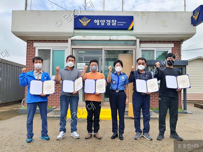 해양경찰서 앞에서 시민들이 표창장을 들고 포즈를 취하고 있다.