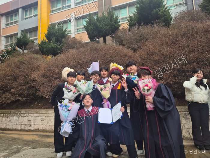 졸업식을 맞이한 학생들이 꽃다발을 들고 기념 촬영을 하고 있다.