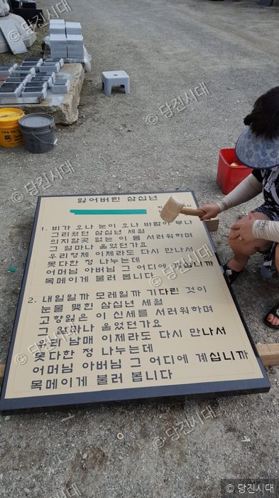 작업자가 석재 비석의 글씨를 다듬고 있다.