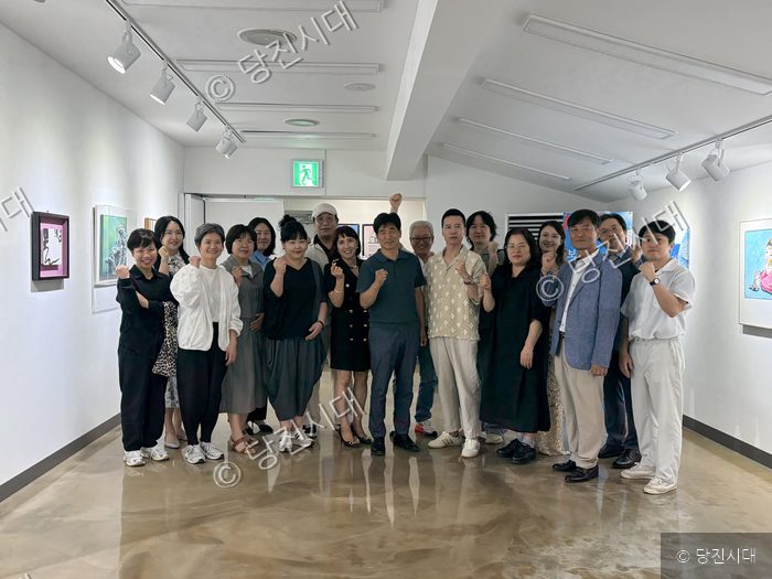 갤러리에서 작가들과 관계자들이 전시회를 기념하며 기념촬영을 하고 있다.