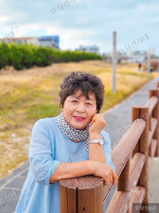 주옥순 합덕읍 궁리 이장이 야외 산책로 난간에 기대어 미소 짓고 있다.