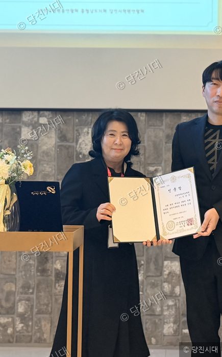 당진시 학원연합회 신임 회장 취임식에서 여성이 인증장을 들고 기념 촬영을 하고 있다.