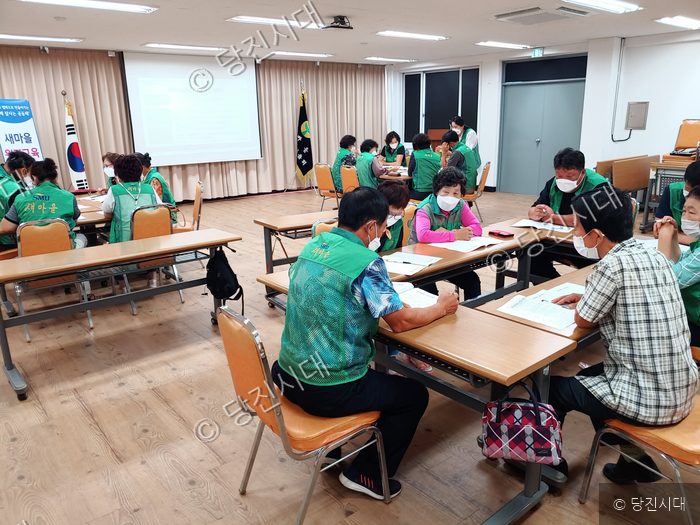 사람들이 강의실에 모여 새마을운동 원격 교육을 받고 있다.