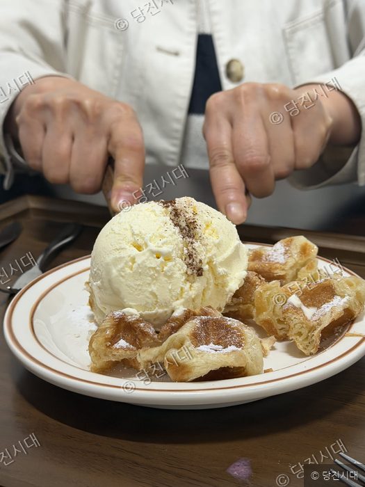 커피숍 대표가 크로플과 아이스크림을 자르고 있다.