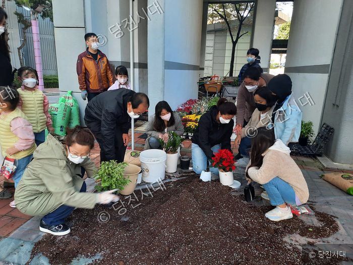 주민들이 야외에 모여 화분에 식물을 심고 가꾸고 있다.