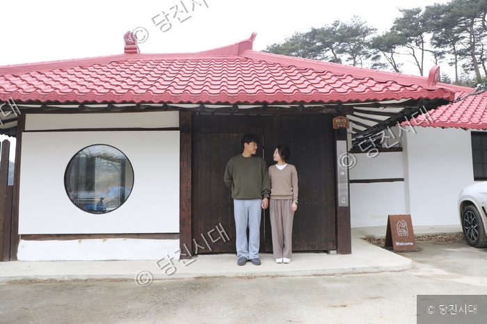 감성스테이 산아래 펜션 앞에서 남녀가 나란히 서 있다.