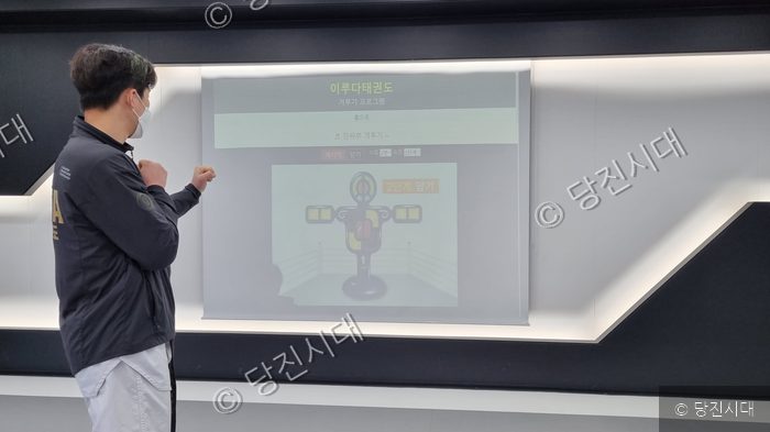 태권도장의 관원이 스크린을 보며 겨루기 프로그램을 체험하고 있다.