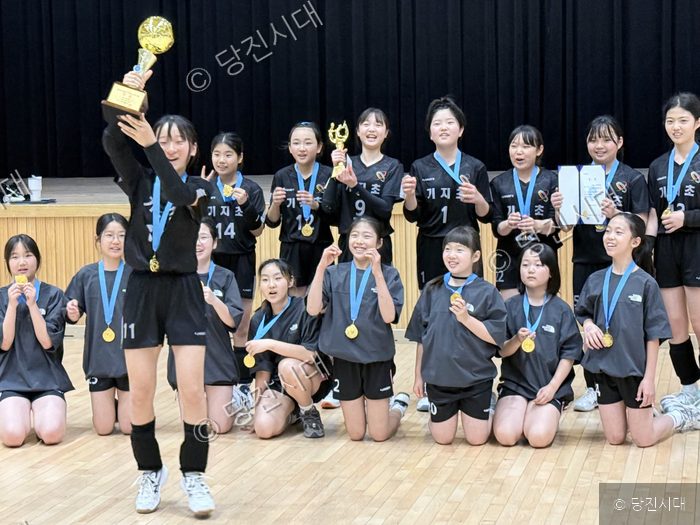기지초등학교 여자 배구부 선수들이 우승 트로피와 메달을 들고 기뻐하고 있다.