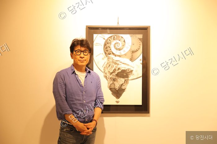 이동섭 작가가 자신이 출품한 미술 작품 앞에서 포즈를 취하고 있다.